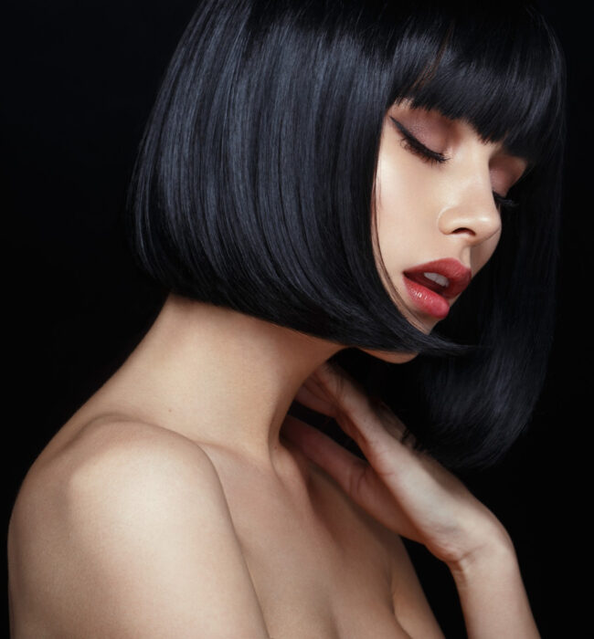 profile-of-a-sensual-model-in-black-wig-closed-eyes-touches-his-neck-naked-shoulders-isolated-on-black-background